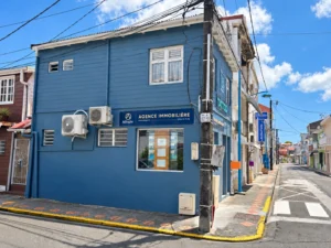 Façade bleue et vitrine ALLOGIA à l’angle des deux rues à Sainte-Luce.